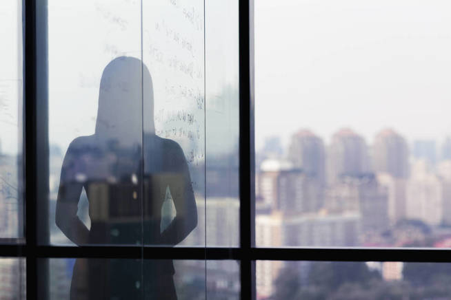 silhouette-shadow-of-woman-looking-at-city-from-office